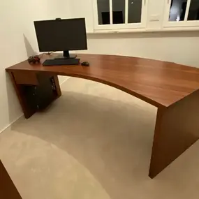 Großer gebogener Holz-Schreibtisch im Homeoffice mit Monitor und Tastatur