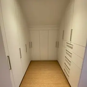 Begehbarer Kleiderschrank mit weißen Einbauschränken und Schubladen
