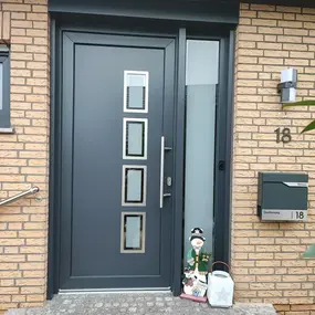 Moderne graue Haustür mit Glasfenstern, Briefkasten und Hausnummer 18
