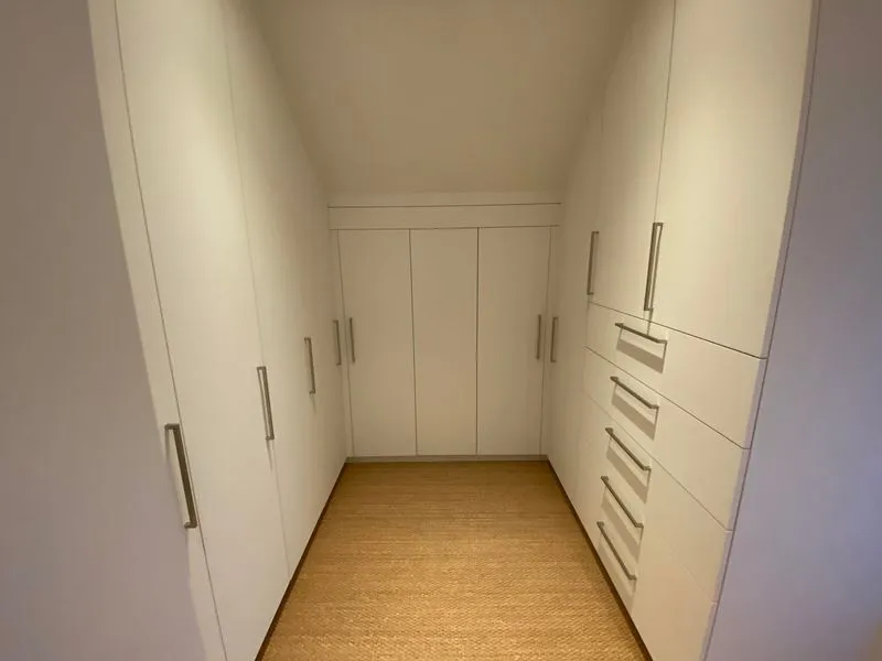 Begehbarer Kleiderschrank mit weißen Einbauschränken und Schubladen
